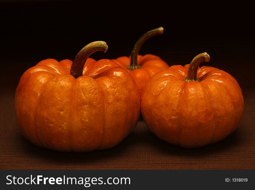 Three pumpkins against a dark background. Three pumpkins against a dark background