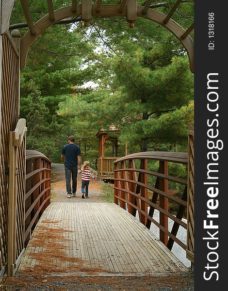 Father and child holding hands walking over bridge. Father and child holding hands walking over bridge.