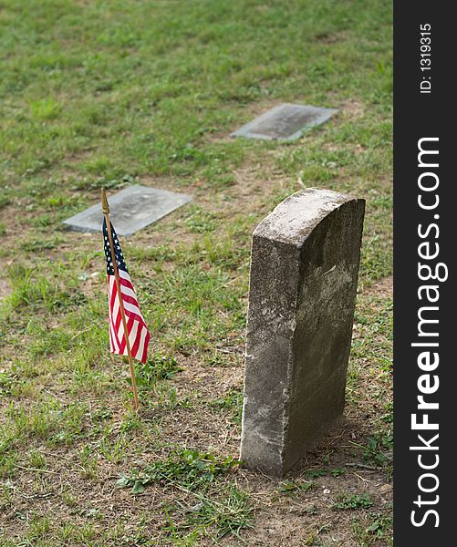 A tombstone or grave marker with an United States of America US Flag. A tombstone or grave marker with an United States of America US Flag.