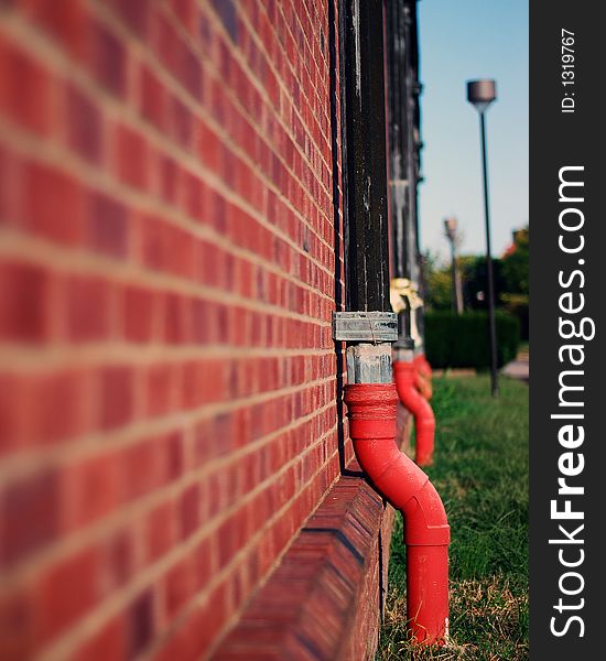 Pipes on a red brick wall with some sky background