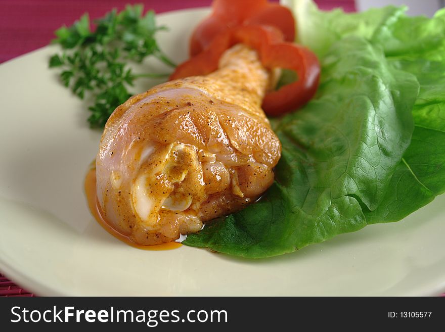 Chicken leg on plate with spices.