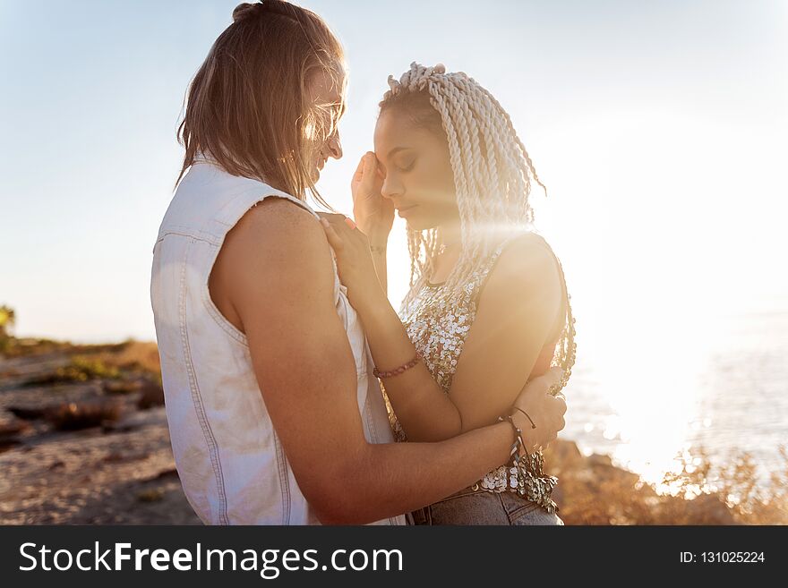 Stylish young woman with dreadlocks hugging her strong handsome man