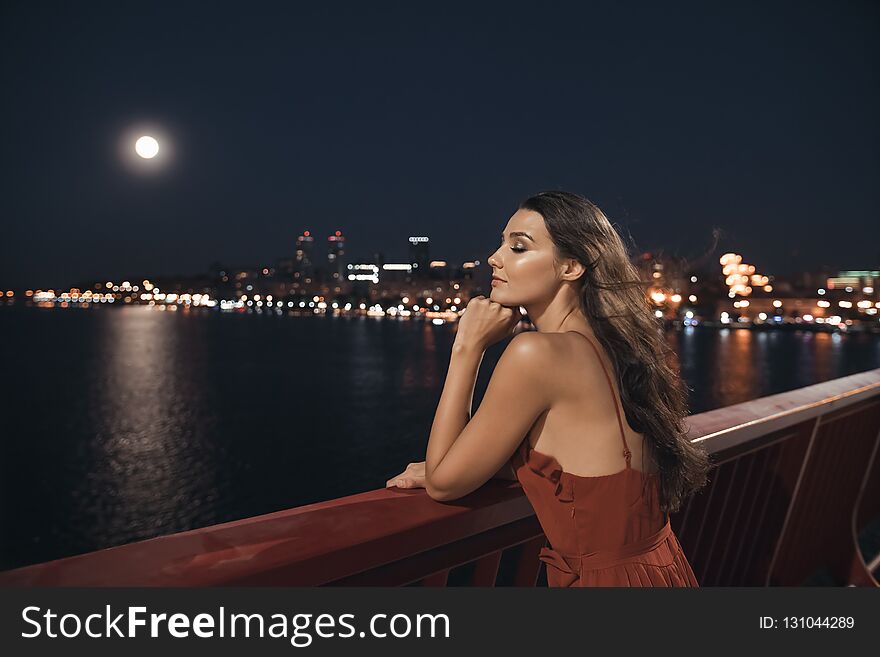 Young ellegant woman standing on the ligths of the night city background. Freedom and girl in love concept