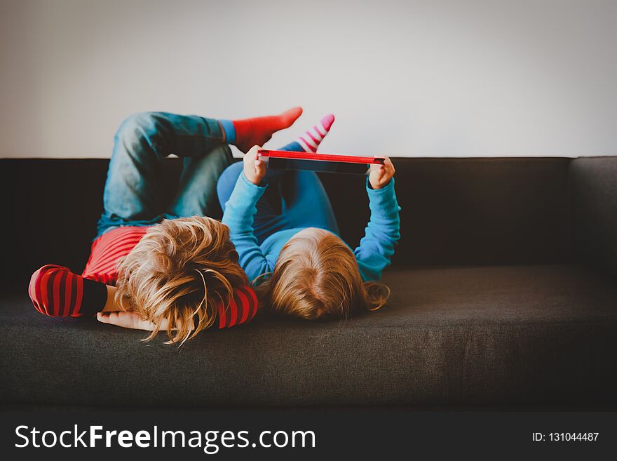 Little Boy And Girl Looking At Touch Pad At Home