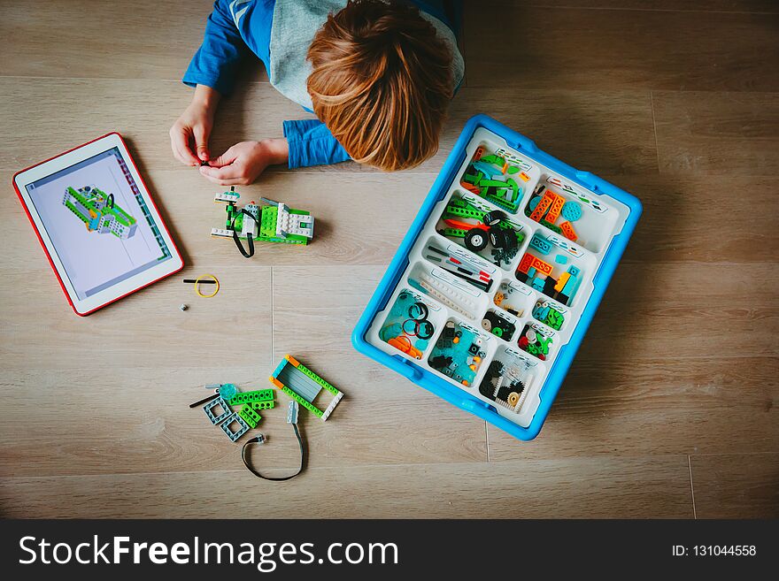 Little boy building robot from plastic blocks and programming it with touch pad. Little boy building robot from plastic blocks and programming it with touch pad