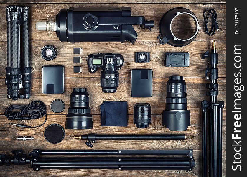 Set of the camera and photography equipment  tripod, filter, flash, camera lens, memory card, hard desk, reflector on wood desk. Professional photographer accessories background.