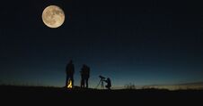 Friends With Campfire Looking On Big Moon Royalty Free Stock Images