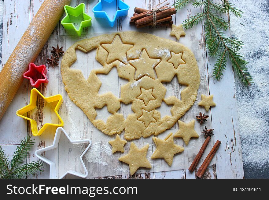 Baking Christmas gingerbread, flour sprinkled dough on a wooden table, molds in the form of stars