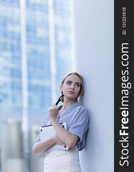 A beautiful woman standing in the center of the city holding a notebook in her hands. A beautiful woman standing in the center of the city holding a notebook in her hands