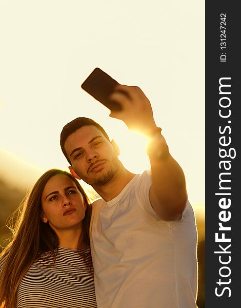 Romantic couple taking a selfie with mobile during sunset. Romantic couple taking a selfie with mobile during sunset