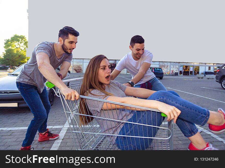 Full length portrait of a young men pushing a women in a shopping cart. Full length portrait of a young men pushing a women in a shopping cart