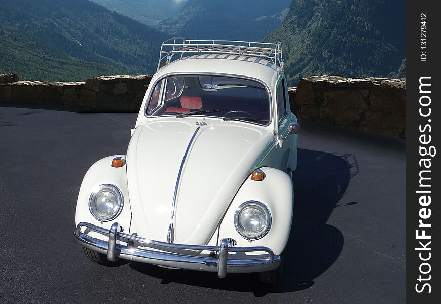 Volkswagen Beetle parked in front of tall mountains in the distance. Volkswagen Beetle parked in front of tall mountains in the distance.