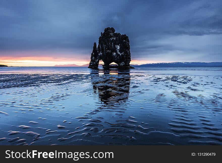 Hvitserkur is a spectacular rock in the sea on the Northern coast of Iceland. Legends say it is a petrified troll. On this photo Hvitserkur reflects in the sea water after the midnight sunset.