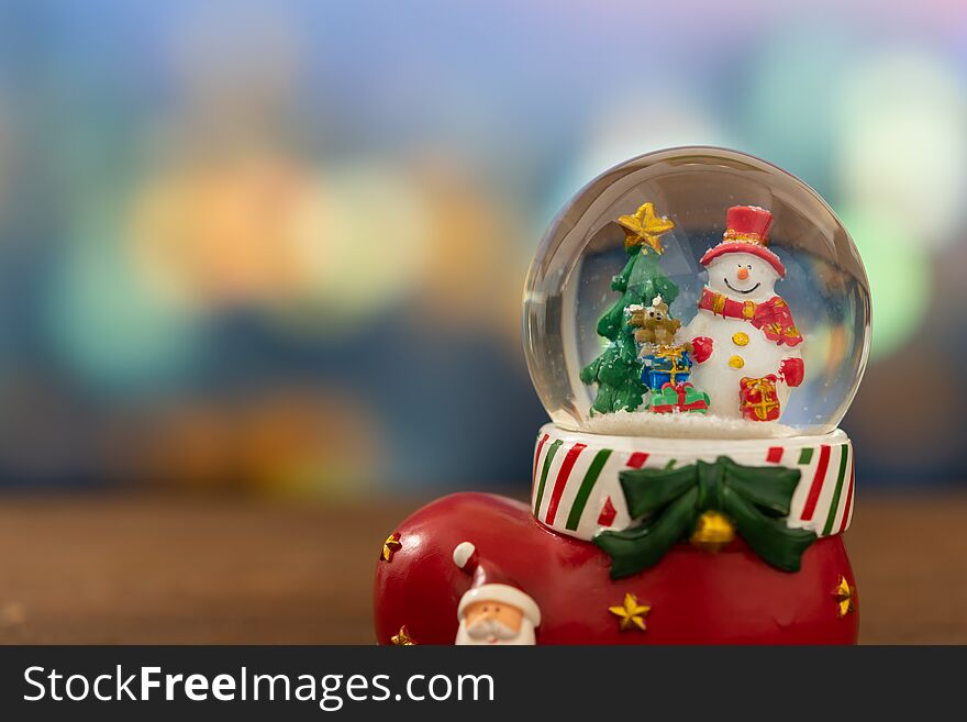 Christmas tree and snowman in snow globe ball with bokeh background.