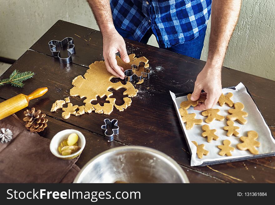 Christmas food concept. Man cooking gingerbread man cookies in Christmas wooden table in the home kitchen. Xmas dessert. Christmas food concept. Man cooking gingerbread man cookies in Christmas wooden table in the home kitchen. Xmas dessert