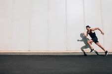 Young Man Runner Running Along Wall With Copy Space Stock Photography