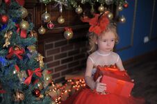 Girl At The Christmas Tree In A Red Elegant Dress With A Box With Gifts In Her Hands Royalty Free Stock Photo