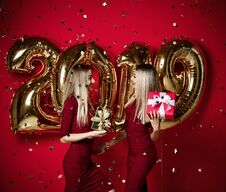 Two Women Celebrating At New Year Party Happy Laughing Girls In Casual Dresses Throw Gold Stars Confetti With 2019 Balloons Stock Photos