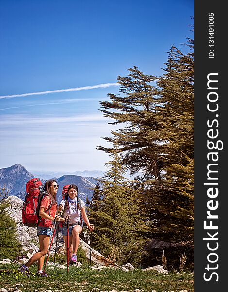 Summer hike in the mountains with a backpack and tent along the path to the top.