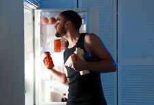 Man Taking Products Out Of Refrigerator In Kitchen Stock Photo