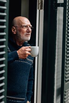 Senior Person Standing Near The Door Drinking Coffee. Old Person Drinking Coffee While Looking Out Of The Door Stock Image