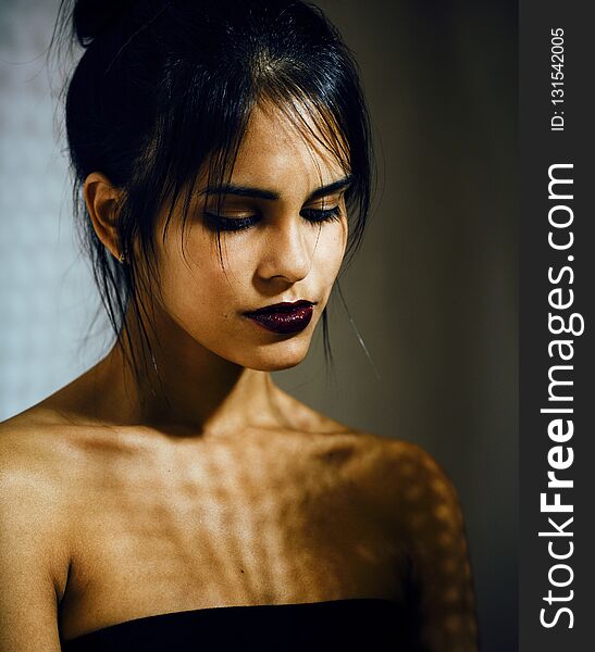 Pretty brunette woman with make up like demon at halloween, closeup scary background concept fashion