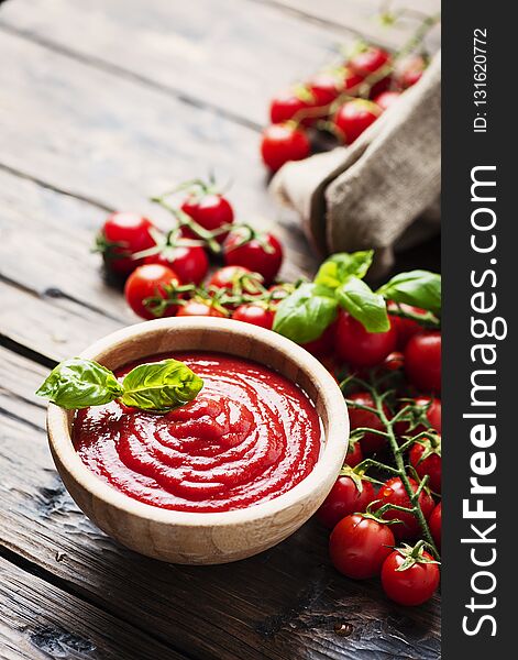 Bowl of tomato sauce and cherry tomatoes on the wooden table, selective focus