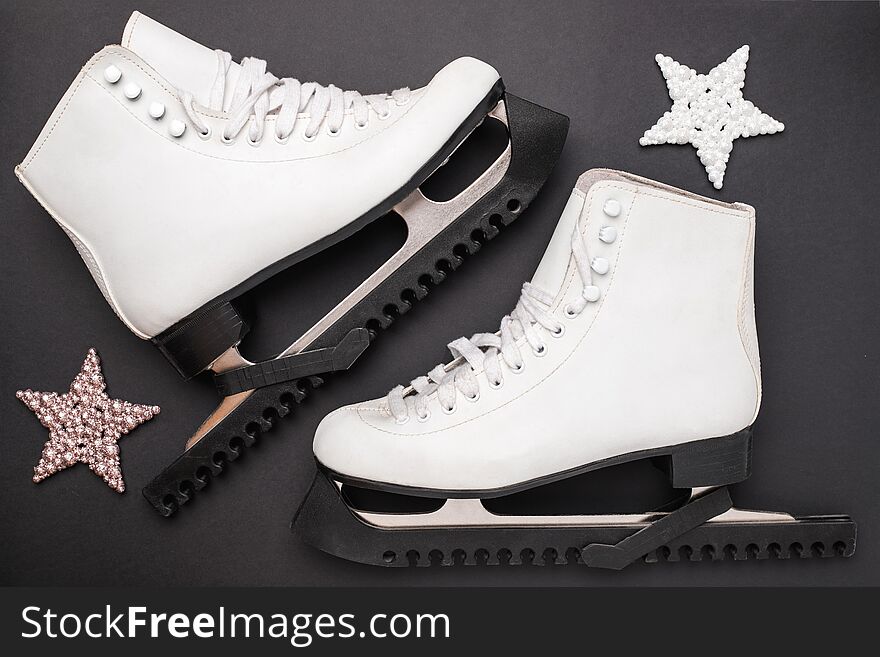 White skates and shiny stars on black background. Concept of healthy life and celebration.