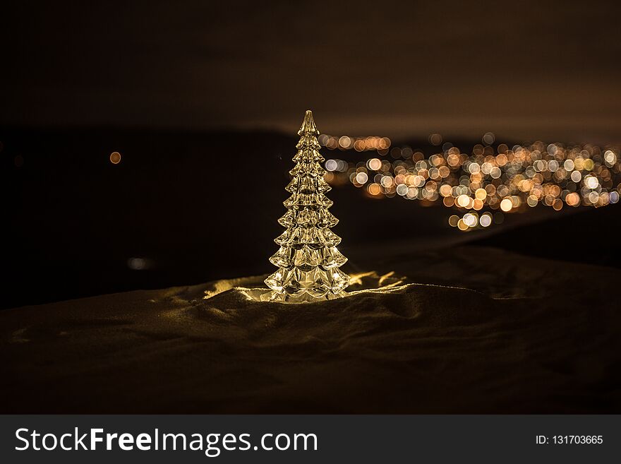Christmas decorations. Fir tree standing on snow with beautiful holiday decorated background and traditional holiday attributes.