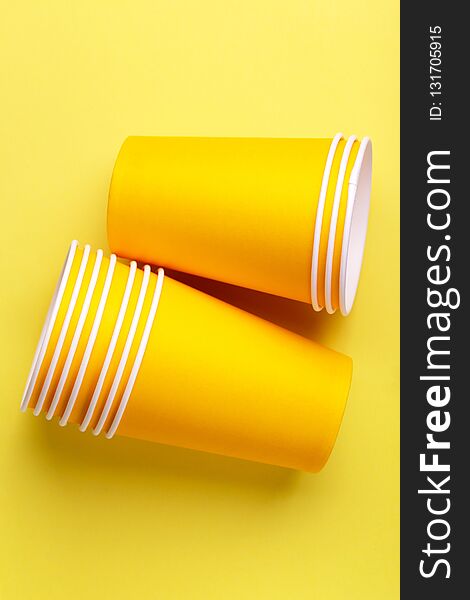 Recycling paper cups for drinks on bright yellow background.