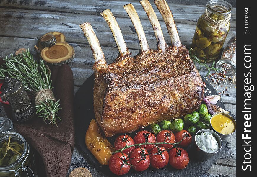 Grilled roasted rack of lamb chops with vegetables, on a wooden surface