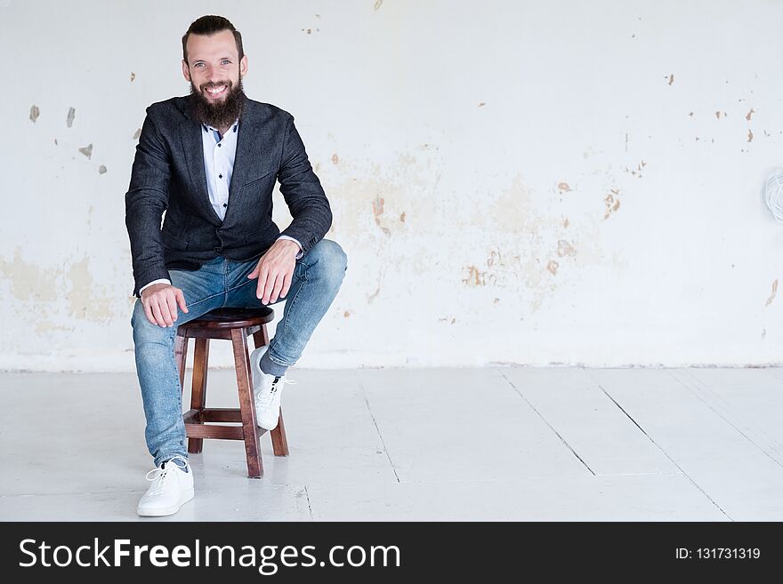 Smiling business man sitting in shabby wall background. success and confidence. modern office workspace. Smiling business man sitting in shabby wall background. success and confidence. modern office workspace.