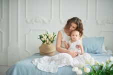 Beautiful Young Mother With Baby Girl In Her Arms. The Concept Of A Happy Family, Motherhood. Mother Playing With Her Baby In The Stock Photo Beautiful Young Mother With Baby Girl In Her Arms. The Concept Of A Happy Family, Motherhood. Mother Playing With Her Baby In The Stock Photo
