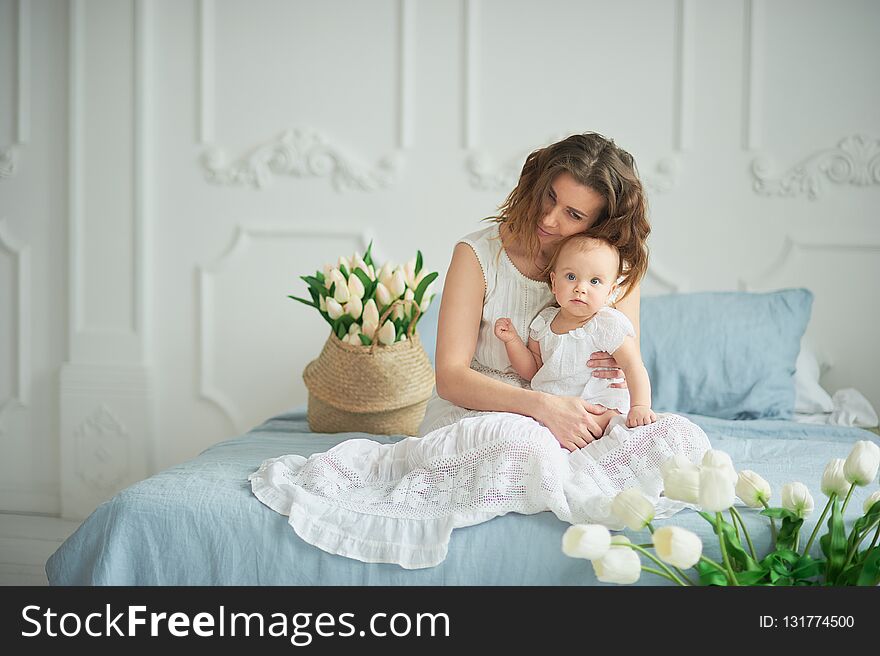 beautiful young mother with baby girl in her arms. The concept of a happy family, motherhood. mother playing with her baby in the bedroom. women& x27;s day