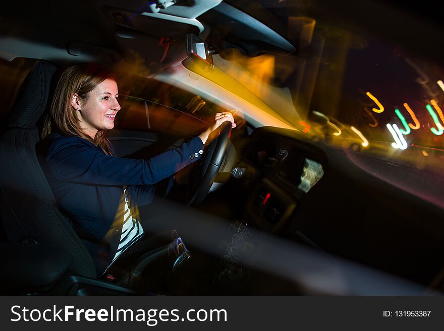 Driving a car at night - pretty, young woman driving her car