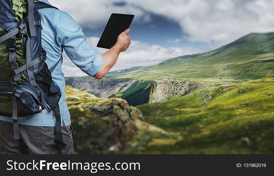 Young traveler hiker with backpack looking at the route map in a digital tablet. The concept of a modern adventure concept