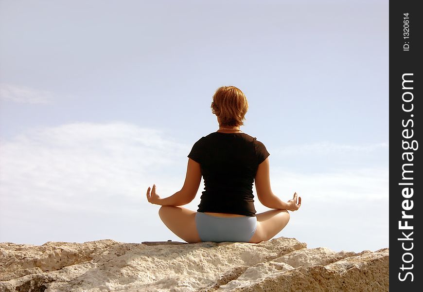 Woman in black meditating on rock. Woman in black meditating on rock