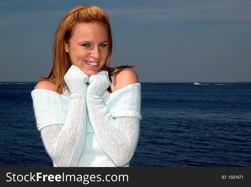 A pretty teen keeping warm in a sweater by the ocean. A pretty teen keeping warm in a sweater by the ocean