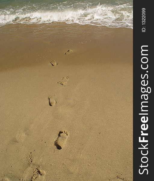 Foot steps on the beach, leading to the sea. Foot steps on the beach, leading to the sea