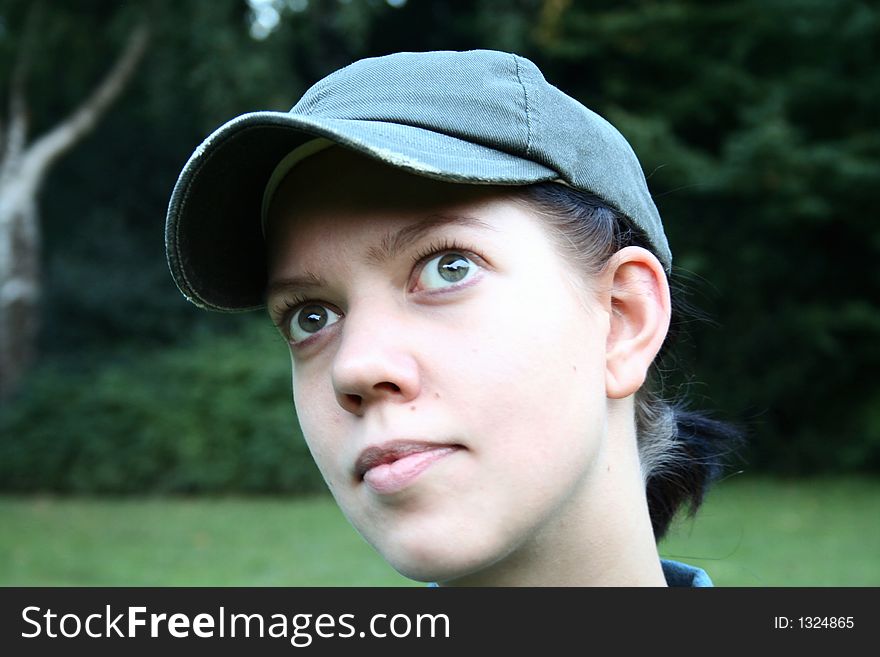 Young woman with cap looking up with nature background