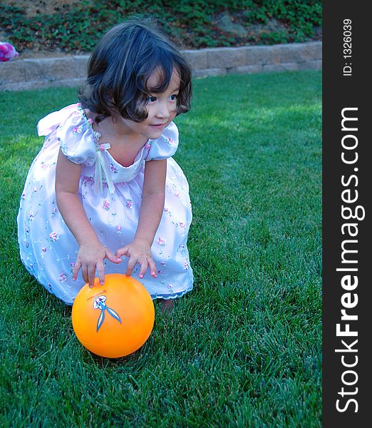 Little girl in beautiful dress is playing ball on the grass. Little girl in beautiful dress is playing ball on the grass