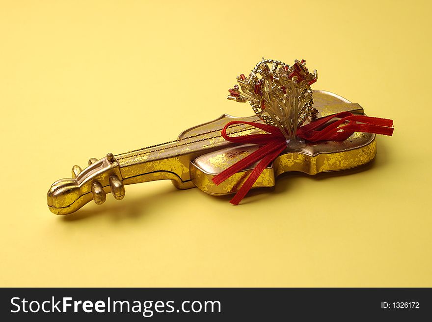 A golden violin decoration on yellow background. A golden violin decoration on yellow background