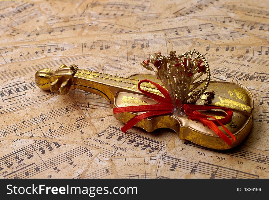 Golden violin decoration on torn sheets of musical scores. Golden violin decoration on torn sheets of musical scores