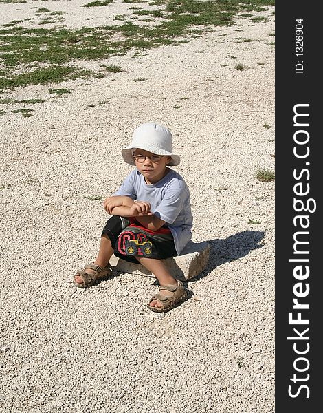 A young boy sits on the stone. A young boy sits on the stone