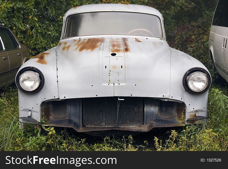 Circa 1950 car missing front end parts sitting in weeds. Circa 1950 car missing front end parts sitting in weeds