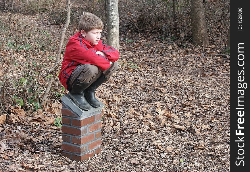 A young boy sitting alone in the park. A young boy sitting alone in the park