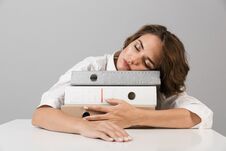 Bored Tired Young Woman Sitting At The Table Isolated Over Grey Background Sleeping On Folders Stock Photo