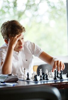 Cute Handsome Boy In White T Shirt Plays Chess With His Rival In Chess Class. Education Concept, Intellectual Game. Royalty Free Stock Images