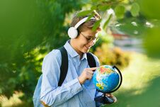 Young Boy In Blue Shirt And Round Glasses Looks And Points On Globe In His Hands. Education, Back To School Stock Photos Young Boy In Blue Shirt And Round Glasses Looks And Points On Globe In His Hands. Education, Back To School Stock Photos