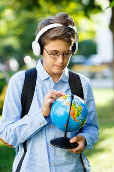 Young Boy In Blue Shirt And Round Glasses Looks And Points On Globe In His Hands. Education, Back To School Stock Photos